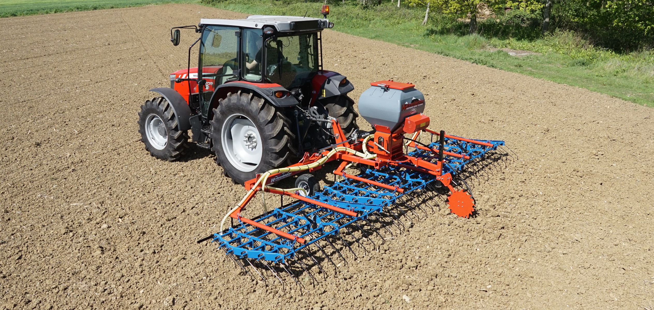 OPICo Grass Harrow and Air Seeder mounted to a Massey Ferguson tractor in cultivated field